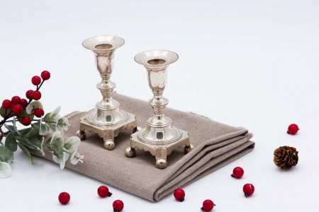 Par de castiçais baixos em prata com base quadrangular e assentes em quatro pés em forma de bolas.