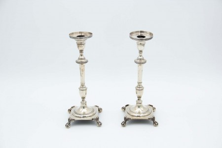 Par de castiçais em prata de fustes torneados,  bases quadradas com quatro pontos de suporte cada em forma de garras e  arandeals e base frisados