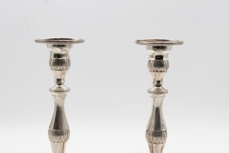 Castiçais de prata com fustes torneados e motivos vegetalistas gravados assentes em bases quadradas com quatro pés em forma de garras.