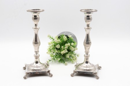 Castiçais de prata com fustes torneados e motivos vegetalistas gravados assentes em bases quadradas com quatro pés em forma de garras.