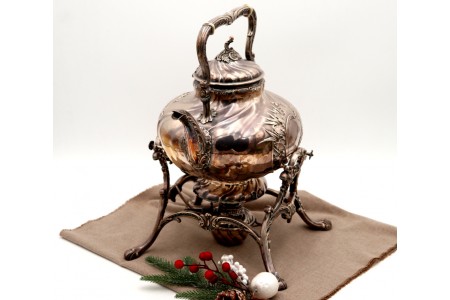 Chaleira em prata com relevos gomados e aplicações, trempe, corpo aspiralado, lamparina na base e assente em quatro pés alteados.