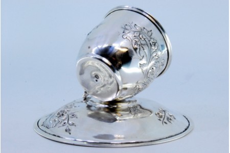 Chávena com pires em prata com relevos, cabo com torcidos e interior em dourado.