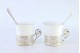  Chávenas em porcelana com suportes em prata e duas colheres de café com estojo próprio.