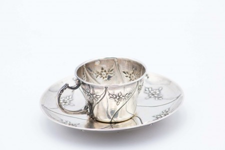 Chávena de chá em prata com pires relevados de apontamentos de florais.