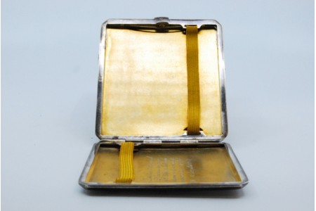 Cigarreira em prata com bandas ao longo com o interior dourado e tampa basculante.