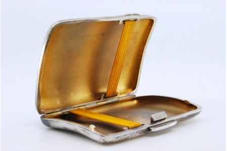 Cigarreira em prata de formato curvo com gravados guilhochados, dourado no interior e tampa basculante.