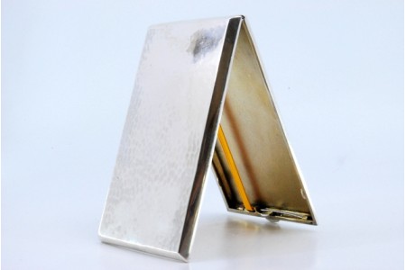 Cigarreira em prata martelada com interior dourado, duas fitas para suporte dos cigarros e tampa basculante.