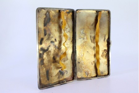Cigarreira em prata com frisos ao alto, tampa basculante e interior dourado.