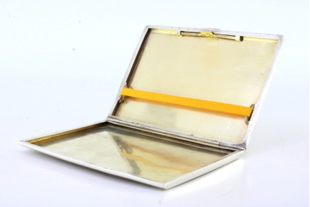 Cigarreira em prata guilhochada com aplicação para abertura e interior dourado.