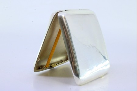 Cigarreira em prata guilhochada com bandas ao alto de formato curvo e interior dourado.