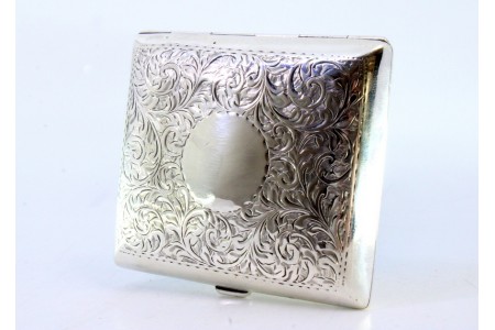Cigarreira em prata com relevos florais e grinaldas envolvendo cartela para monograma formato curvo e interior dourado.