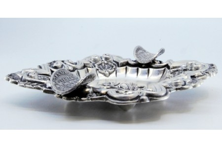 Cinzeiro em prata com aplicações ao redor taça com cobra ao centro e duas moedas como suportes