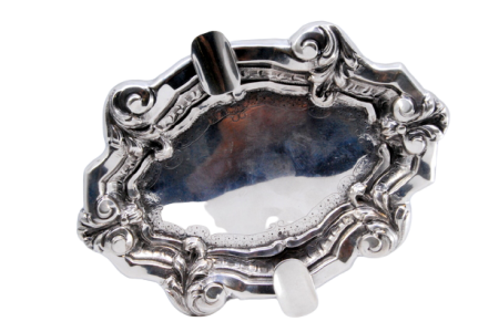 Cinzeiro em prata com relevos concheados, gravados no centro e dois suportes para cigarros.