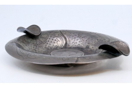 Cinzeiro em prata com gravados decorado com três moedas.