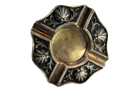 Cinzeiro em prata com relevos em forma de conchas e quatro apoios para cigarros.