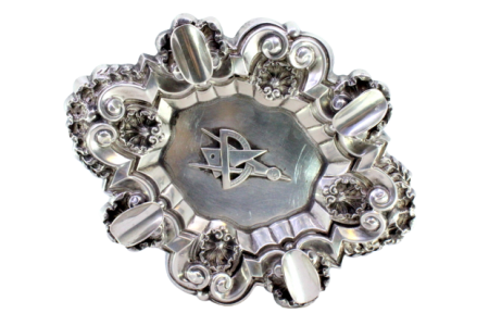 Cinzeiro em prata concheada com relevos, quatro suportes para cigarros e símbolo maçónico no centro.