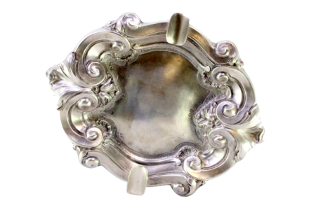 Cinzeiro em prata com relevos concheados e dois suportes para cigarros.