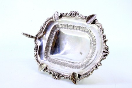 Cinzeiro em prata com folhas de acanto relevadas na envolvência recortada, quatro suportes para cigarros e assente em quatro pés altos com aplicação.