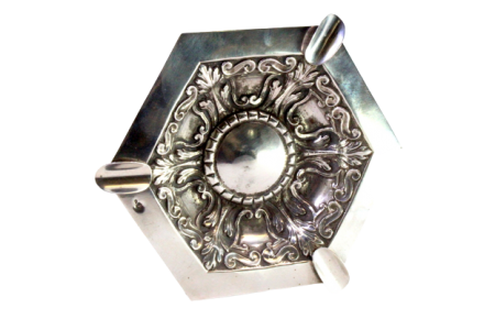 Cinzeiro em prata com relevos envolvendo cartela para monograma ao centro e três suportes para cigarros.