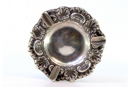 Cinzeiro em prata concheada com relevos e três suportes para os cigarros.