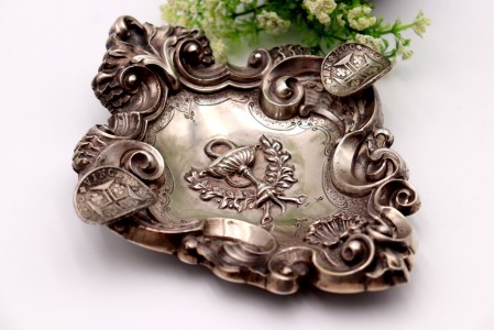 Cinzeiro em prata com relevos concheados e símbolo ao centro