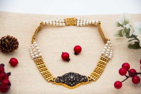  Colar de ouro com segmentos alternados com pérolas de cultura e medalhão central em prata com lascas de diamante e diamante em talhe brilhante no centro.