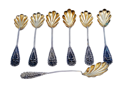 Conjunto de seis colheres de café e pá de açúcar com conchas em forma de folhas douradas e cabos relevados.