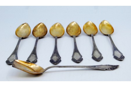 Conjunto de seis colheres de café e pá de açúcar em prata com conchas douradas e relevos nos cabos.