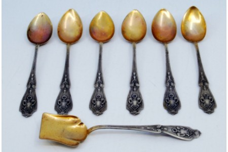 Conjunto de seis colheres de café e pá de açúcar em prata com conchas douradas e cabos relevados.