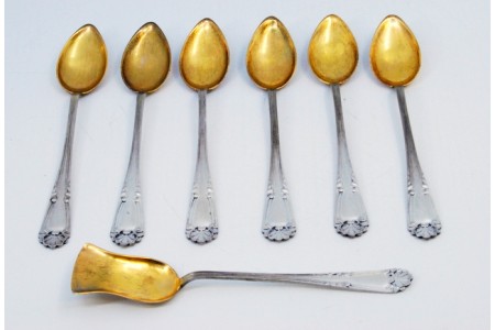 Conjunto de seis colheres de chá e pá de açúcar em prata com conchas douradas e cabos concheados.