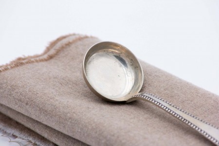 Colher para molhos em prata com frisos de continhas ao longo do cabo.