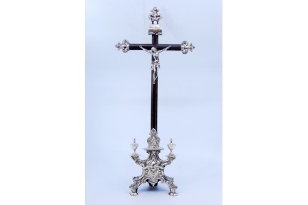Crucifixo em madeira de pau santo com Jesus em prata, símbolos cristãos e assente sobre três pés.