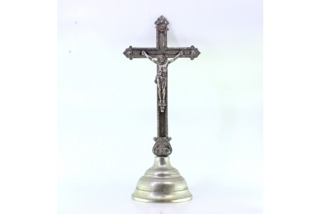 Crucifixo em prata com relevos assente sobre plinto com frisos na envolvência.