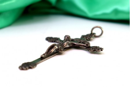 Crucifixo em prata com relevos e aplicações, argola de suspensão.