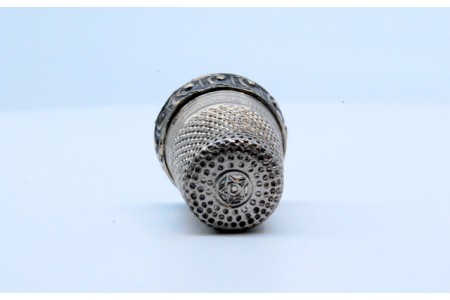 Dedal em prata com relevo no rebordo. 