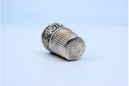 Dedal em prata com relevos de folhas e outras gravuras.