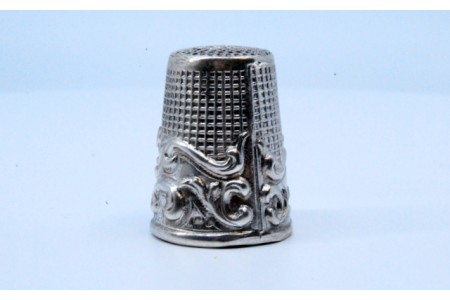 Dedal em prata com volutas relevadas.