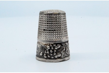 Dedal em prata com gravuras de ramos e folhas.