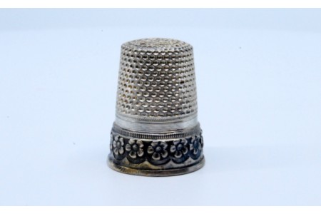 Dedal em prata com flores em relevo.