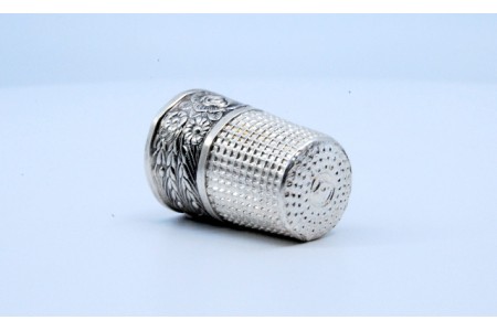 Dedal em prata com ramos e flores em relevo.