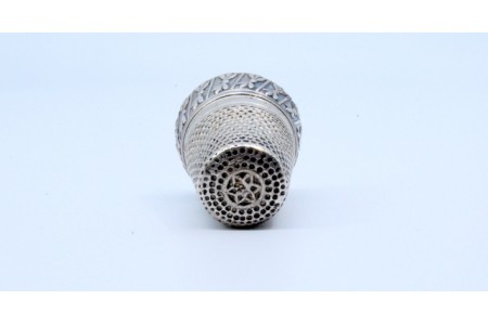 Dedal em prata com floreados em relevo.