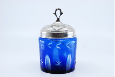 Frasco em vidro azul para compota com gravados e tampa em prata com motivos florais.