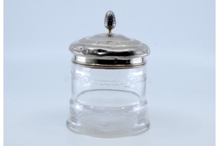 Frasco em vidro com tampa de prata com relevo e pomo em forma de pinha.