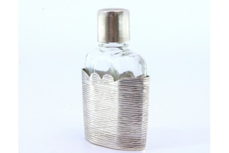 Frasco de perfume em vidro com suporte e tampa em prata com frisos.
