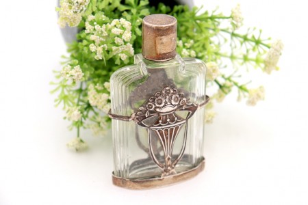 Frasco perfume em vidro com estrutura em prata revelada.
