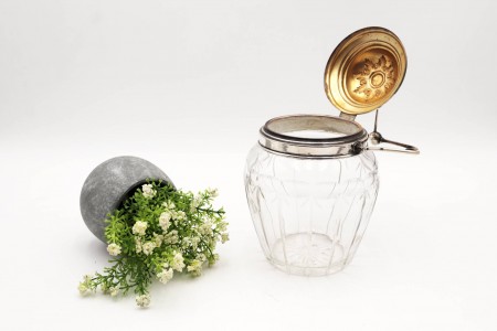 Biscoiteita de vidro com gravados, asa e tampa basculantes em prata e com motivos florais.