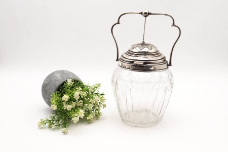 Biscoiteita de vidro com gravados, asa e tampa basculantes em prata e com motivos florais.