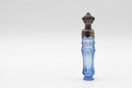 Frasco de perfume em vidro azul com aplicação de prata na tampa e gargalo