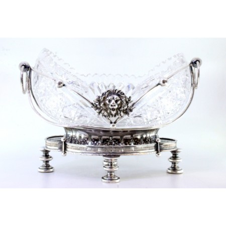 Fruteira em prata com alma em vidro lapidado estrutura com mascarões relevados e aplicações assente em base em gradinha e quatro pés altos em forma circular.