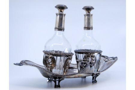 Galheteiro com estrutura em prata em forma de nave com duas galhetas em vidro canelado e assente sobre base perlada com quatro pés zoomórficos.